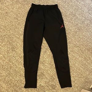 Black joggers with zippers on lower legs. Has pockets, size small